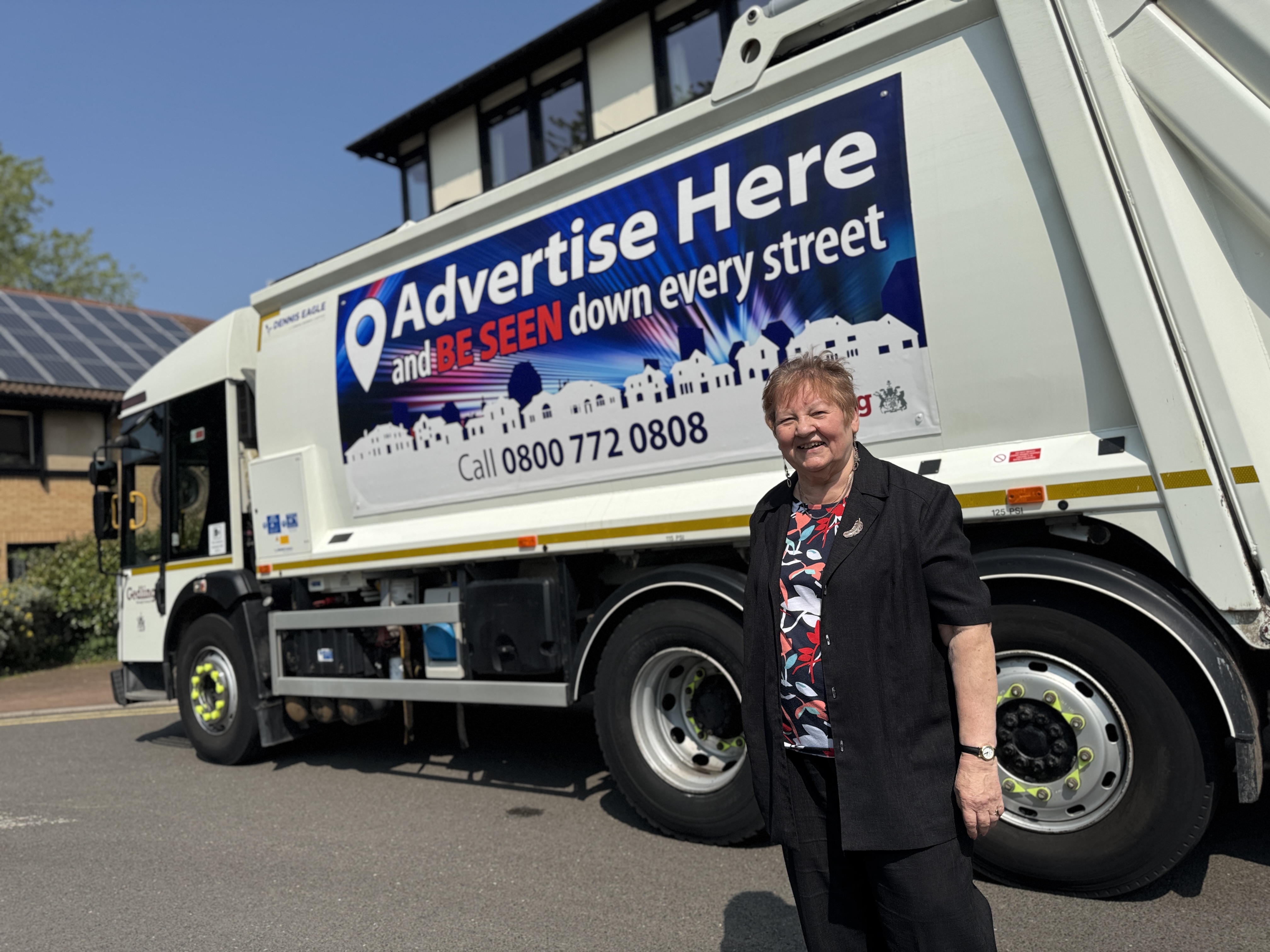 Cllr Marje Paling and a refuse lorry with Advertise Here on its side